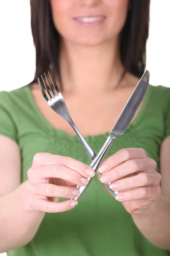 Woman holding up a knife and a fork