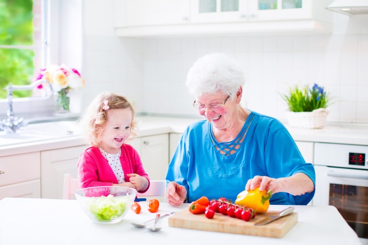 Adorable grandmother and little cute girl making salad